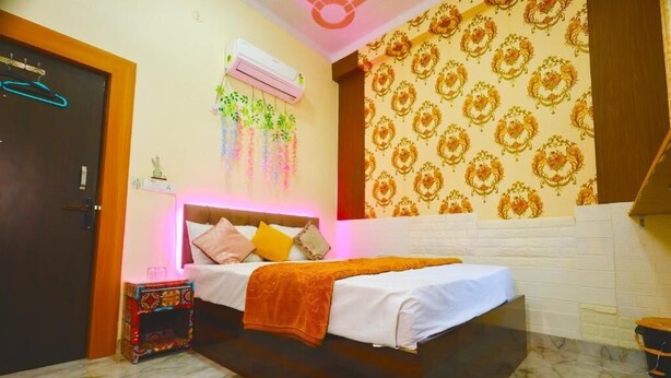 A bedroom with a bed, a small table, an air conditioning unit, and patterned wallpaper. - Sia Taj Hotel Agra Nearest Taj Mahal (Agra)