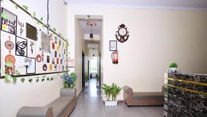 A hallway with a reception desk, a clock, and various wall decorations. - Sia Taj Hotel Agra Nearest Taj Mahal (Agra)
