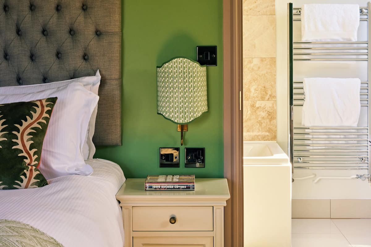 A neatly made bed with a tufted headboard, a bedside lamp, and a small cabinet with a drawer.