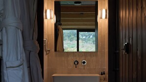 Une salle de bain avec un plancher en bois, une baignoire blanche et une fenêtre au-dessus du lavabo.