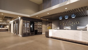 A modern hotel lobby with a reception desk, seating area, and wine display.