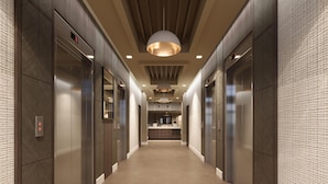 A hallway with elevators and a kitchen area visible in the distance.