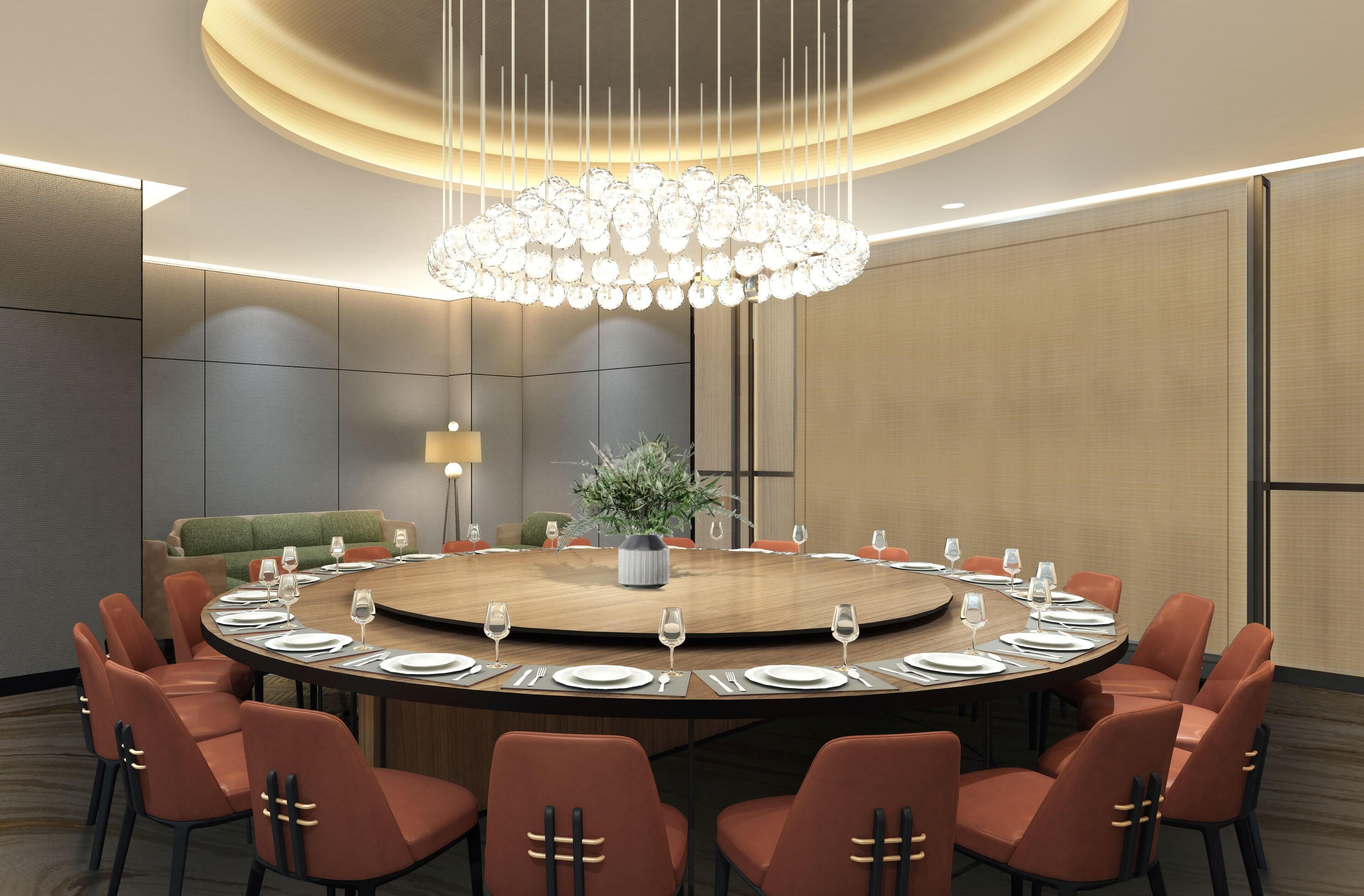 A conference room with a round table, orange chairs, and a chandelier.