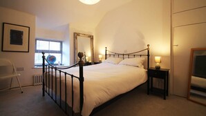 Ein Schlafzimmer mit Himmelbett, einem Globus auf dem Nachttisch, einem Sessel, einer Heizung und einem großen Spiegel an der Wand.