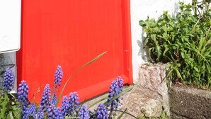 Eine rote Tür mit Fenster, eine weiße Wand und ein kleines Schild.