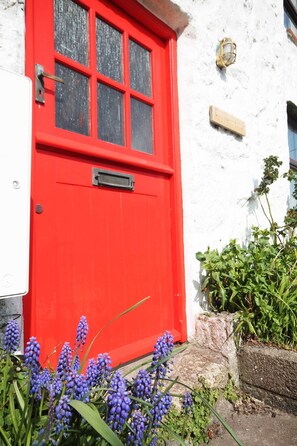 Eine rote Tür mit Fenster, eine weiße Wand und ein kleines Schild.