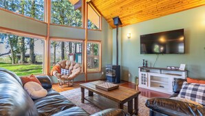 A spacious living room with a large window, a fireplace, a television, and leather furniture.