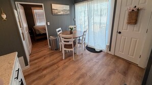 A compact kitchen with a dining area, a small living space, and a door leading to a bedroom. - Low Tide - Heart of Hampton Beach! (Hampton)