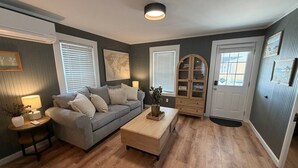A living room with a grey sofa, a wooden coffee table, and a world map on the wall. - Low Tide - Heart of Hampton Beach! (Hampton)