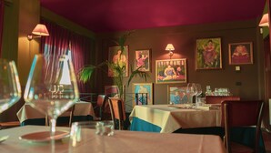 Un restaurante con mesas dispuestas para comer, obras de arte en las paredes e iluminación ambiental cálida.