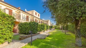 Una hilera de edificios tradicionales de estilo europeo, con un sendero pavimentado y abundante vegetación.