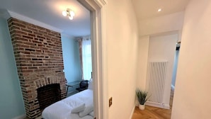 A bedroom with a brick fireplace, a bed, a desk, and a radiator. - Modern 2BDR Home with Garden in Walthamstow (Greater London)