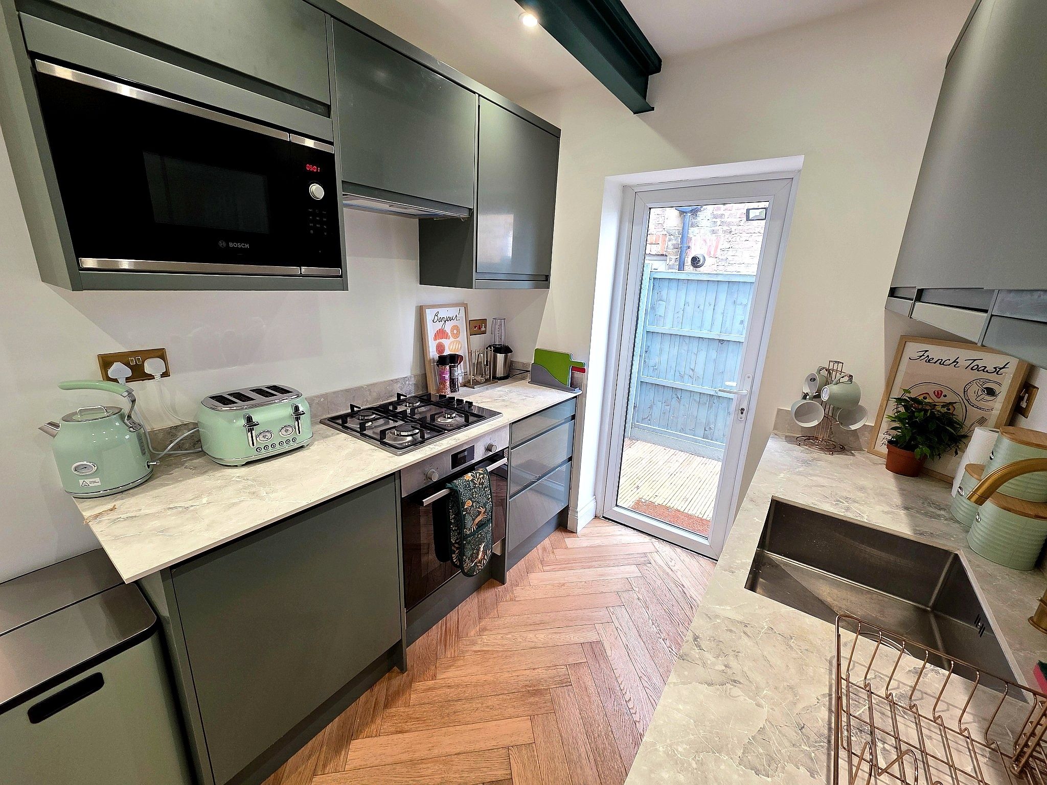 A modern kitchen with a Bosch microwave, a gas stove, and a toaster.