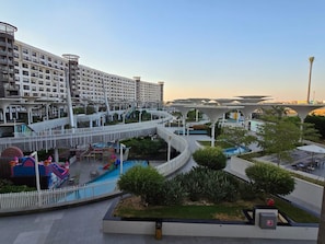 A multi-level hotel with a pool area, outdoor seating, and a bridge connecting different levels.