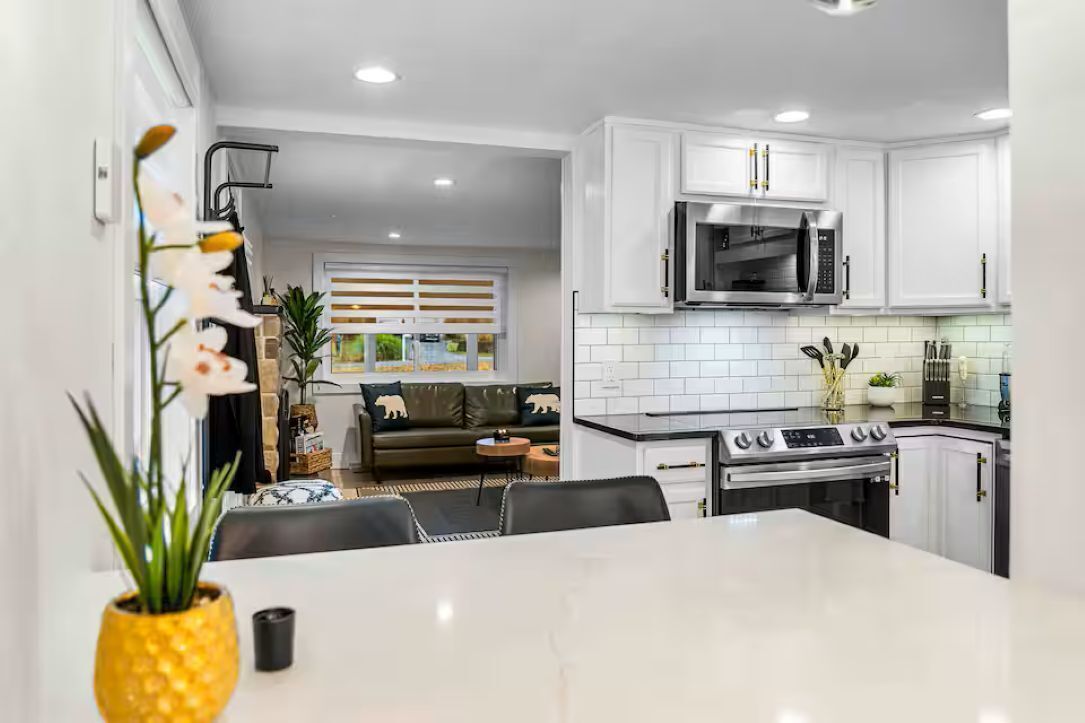 A modern kitchen with white cabinets, a stainless steel microwave, and a gas stove.