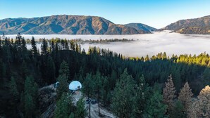 Una estructura abovedada rodeada de un bosque denso y montañas.