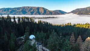 A dome-shaped structure surrounded by dense forest and mountains. - The Domestead- A Romantic Glamping Hideaway (Garden Valley)