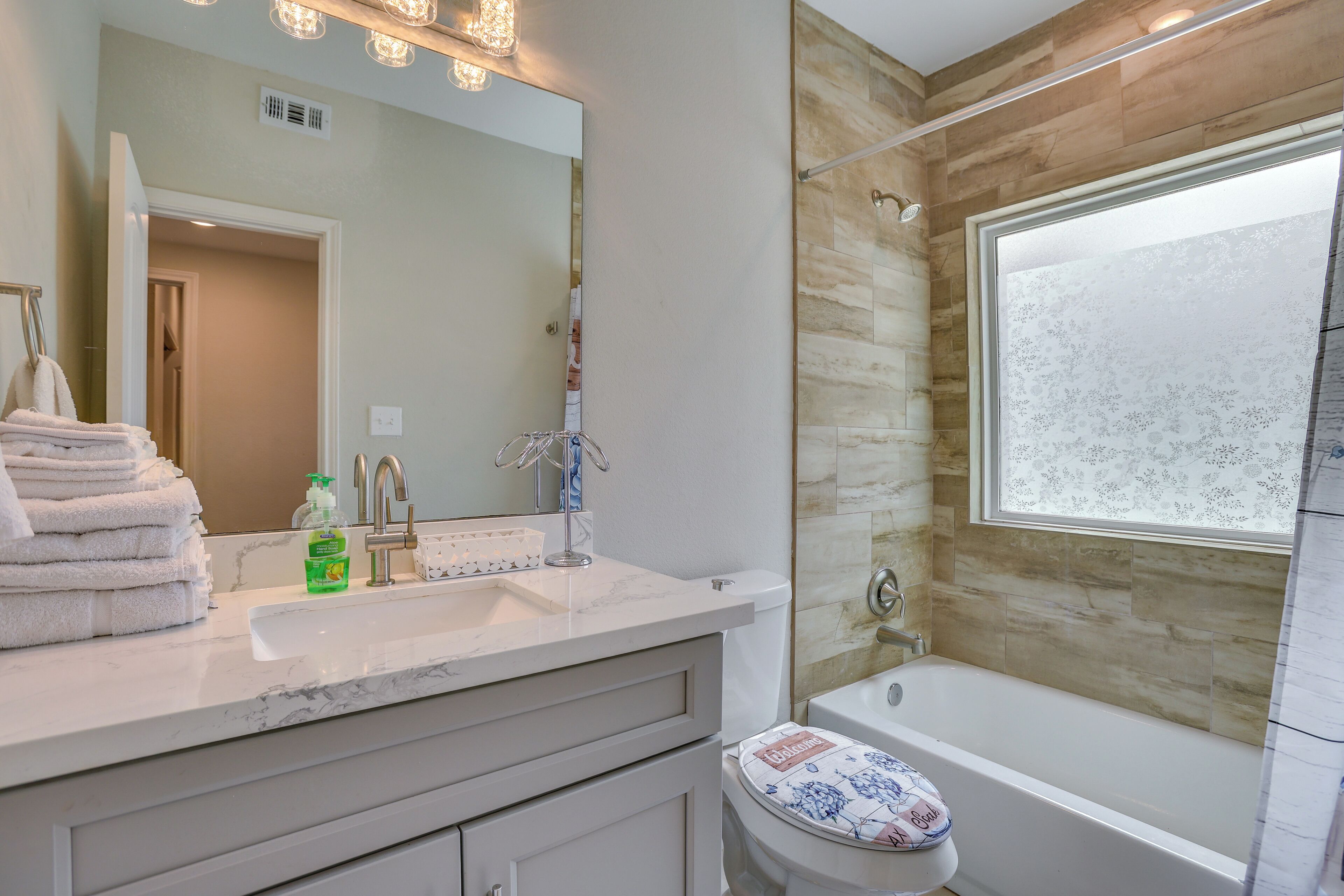 Une salle de bain avec un lavabo blanc, un miroir et une baignoire.