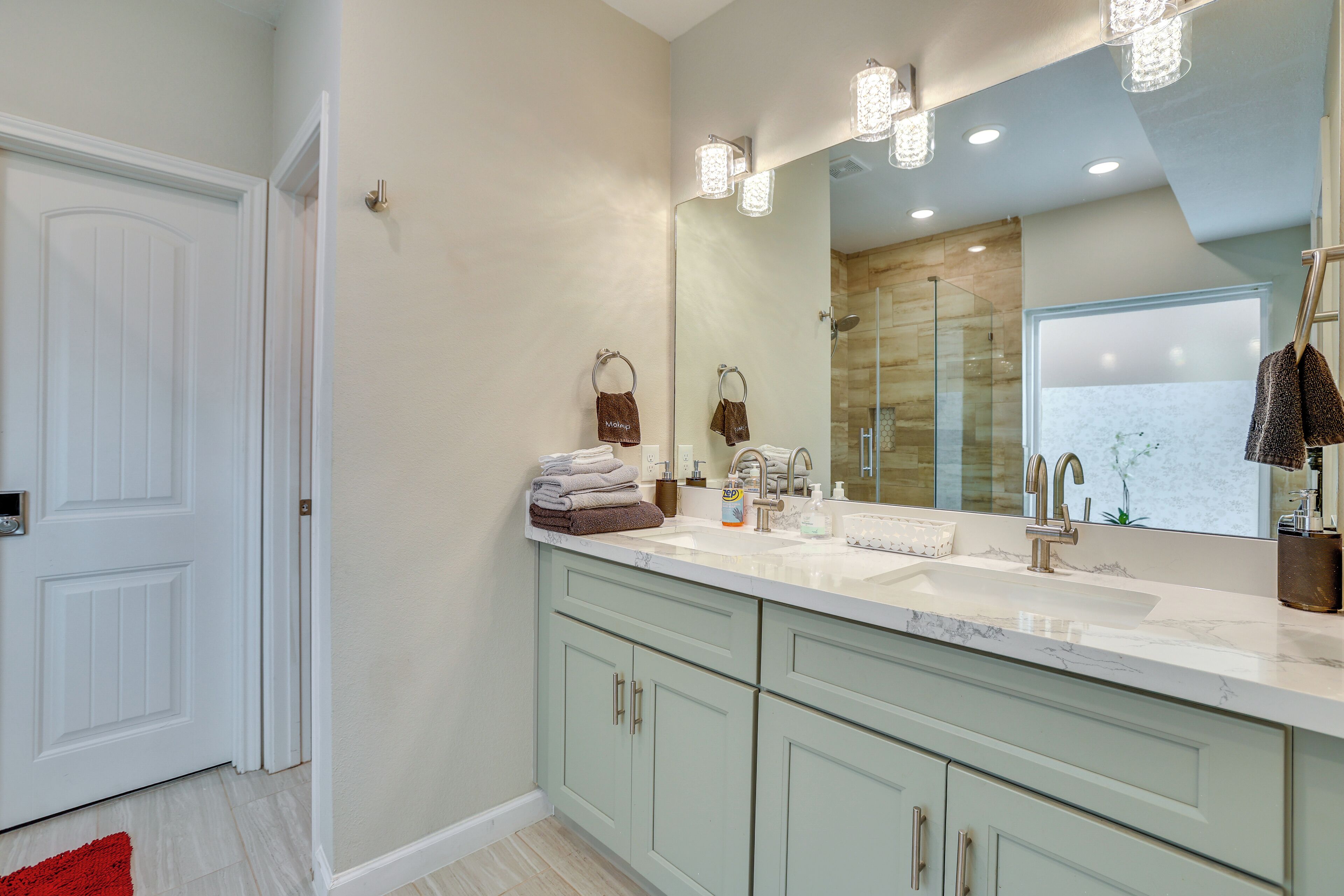 A bathroom with a large mirror, two sinks, and a shower area.