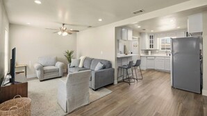 A modern living room with a grey sofa, a television, and a ceiling fan. - Private Fort Worth Getaway Near Stockyards & Zoo! (Fort Worth)