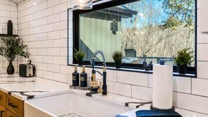 A modern kitchen with white tiles, a large window, and a built-in sink. - Creek Retreat w/ Secluded 18-Acres, Hot Tub, Sauna (East Stroudsburg)