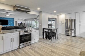 Eine moderne Küche mit weißen Schränken, Edelstahlgeräten, einer Granitabdeckung und einem eingebauten Backofen.