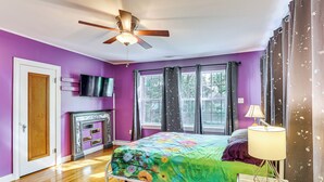 Une chambre à coucher avec un lit, un ventilateur de plafond, une cheminée et un téléviseur fixé au mur.