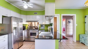 Une cuisine dotée d’un îlot central, d’appareils électroménagers en acier inoxydable et de murs peints en vert.