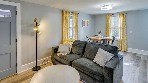 A living room with a gray sofa, a round coffee table, a floor lamp, and a dining area with a table and chairs. - 4 Mi to Waterfront: 2-unit Combo in Kingston! (Kingston)