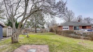 A backyard with a paved patio, a tree, and a house in the background. - 4 Mi to Waterfront: 2-unit Combo in Kingston! (Kingston)