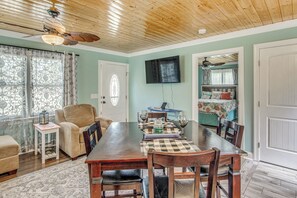 A dining area with a wooden table, chairs, a ceiling fan, and a TV mounted on the wall. - Bolivia Basecamp w/ Patio: 10 Mi to Oak Island (Bolivia)