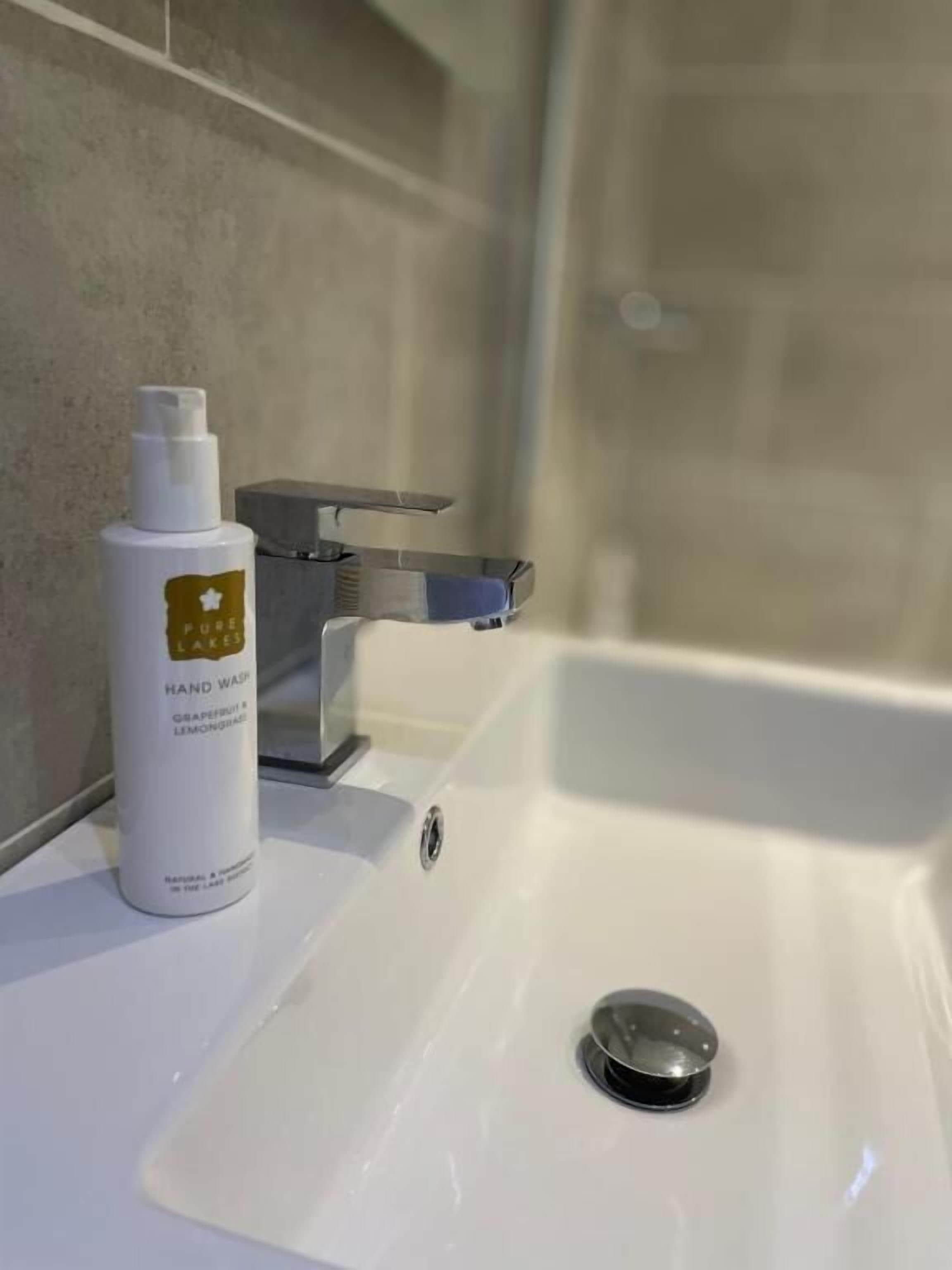 Un lavabo de salle de bain avec un flacon de savon liquide et un robinet.