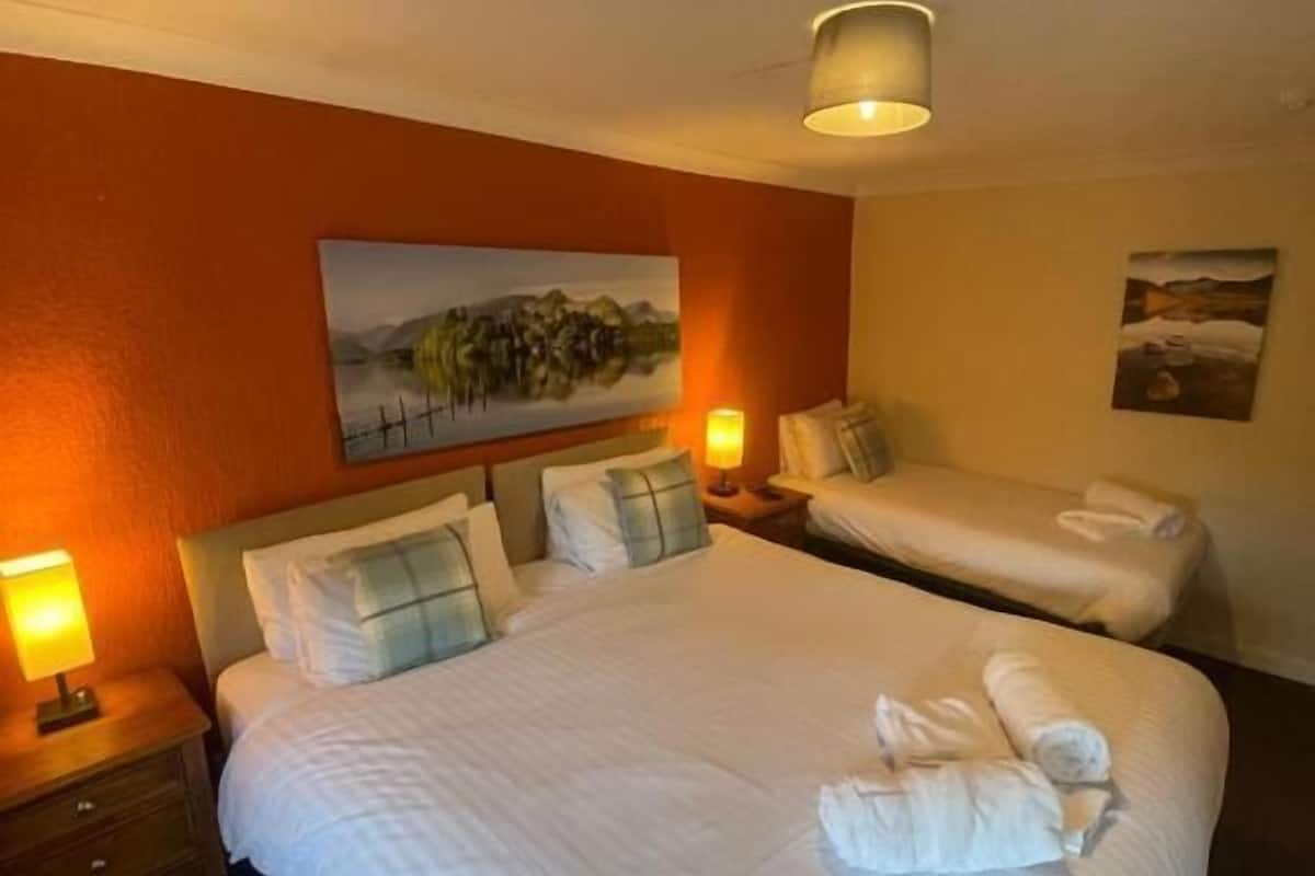 Habitación de hotel con dos camas, un cuadro en la pared y una lámpara a cada lado.