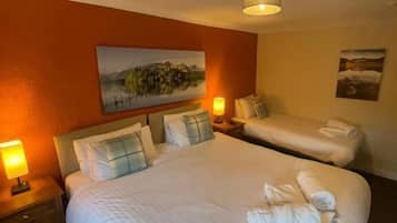 Habitación de hotel con dos camas, un cuadro en la pared y una lámpara a cada lado.