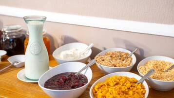 Una mesa de desayuno con diversos alimentos y una jarrón de leche.