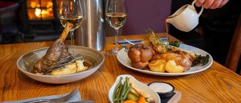 Une table à manger avec des assiettes remplies de nourriture, une bouteille et des verres.