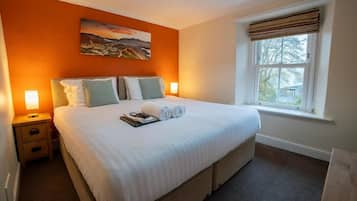 Hotellihuone, jossa on suuri sänky, kaksi yöpöytää, ikkuna, jossa on verhot, ja taulu seinällä.