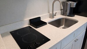 Una cucina con piano cottura integrato, lavello in acciaio inossidabile e macchina per il caffè.
