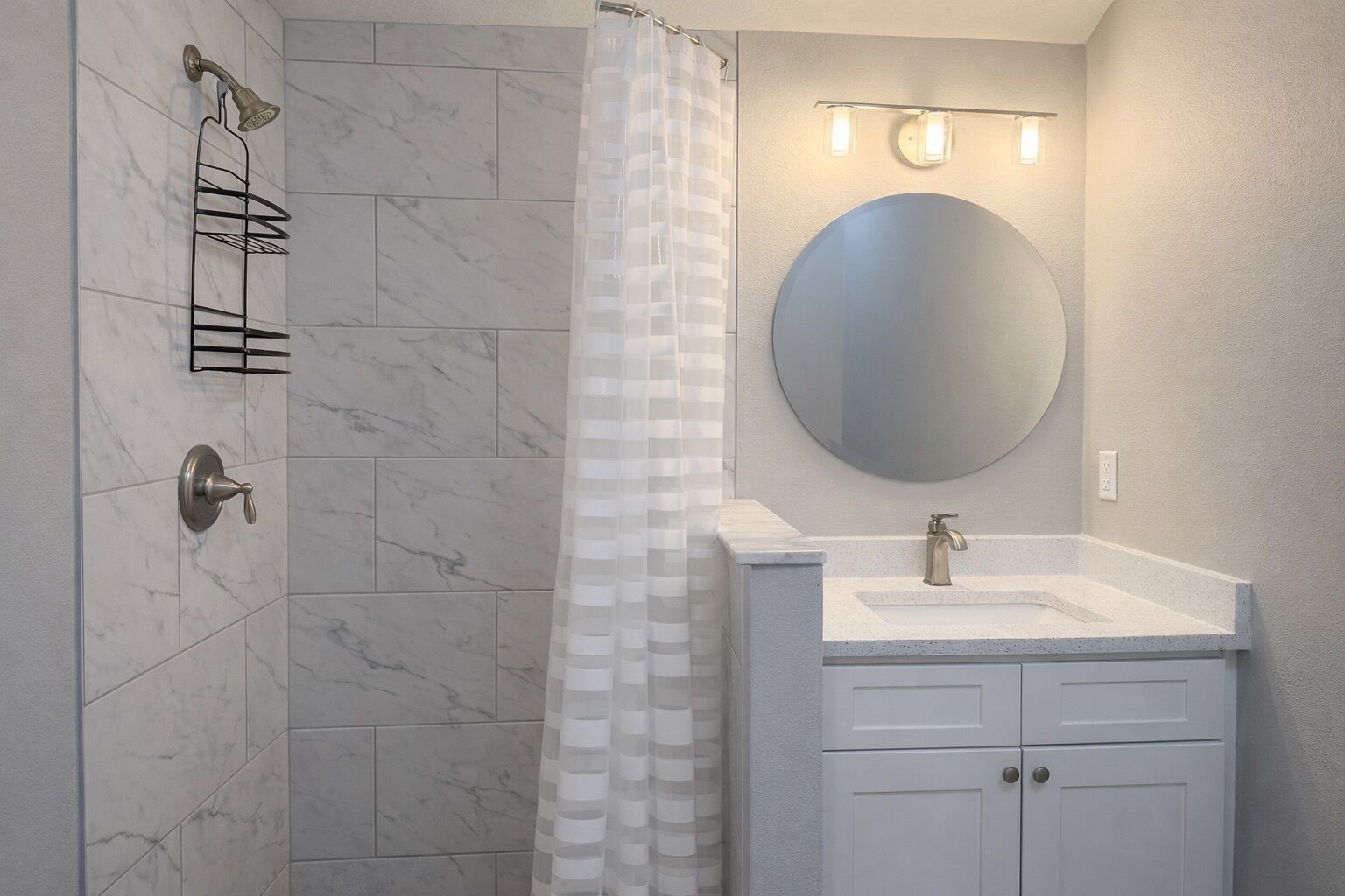 A bathroom with a shower, a sink, a mirror, and a towel rack.