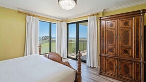 Een slaapkamer met een bed, een houten garderobe en een balkon met uitzicht.