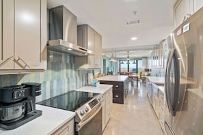 A modern kitchen with a coffee maker, stove, oven, and refrigerator. - Navarre Towers 101 - 3 Bedroom (Navarre)