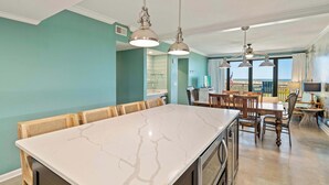 Een keuken met een marmeren aanrecht, houten stoelen en hanglampen.