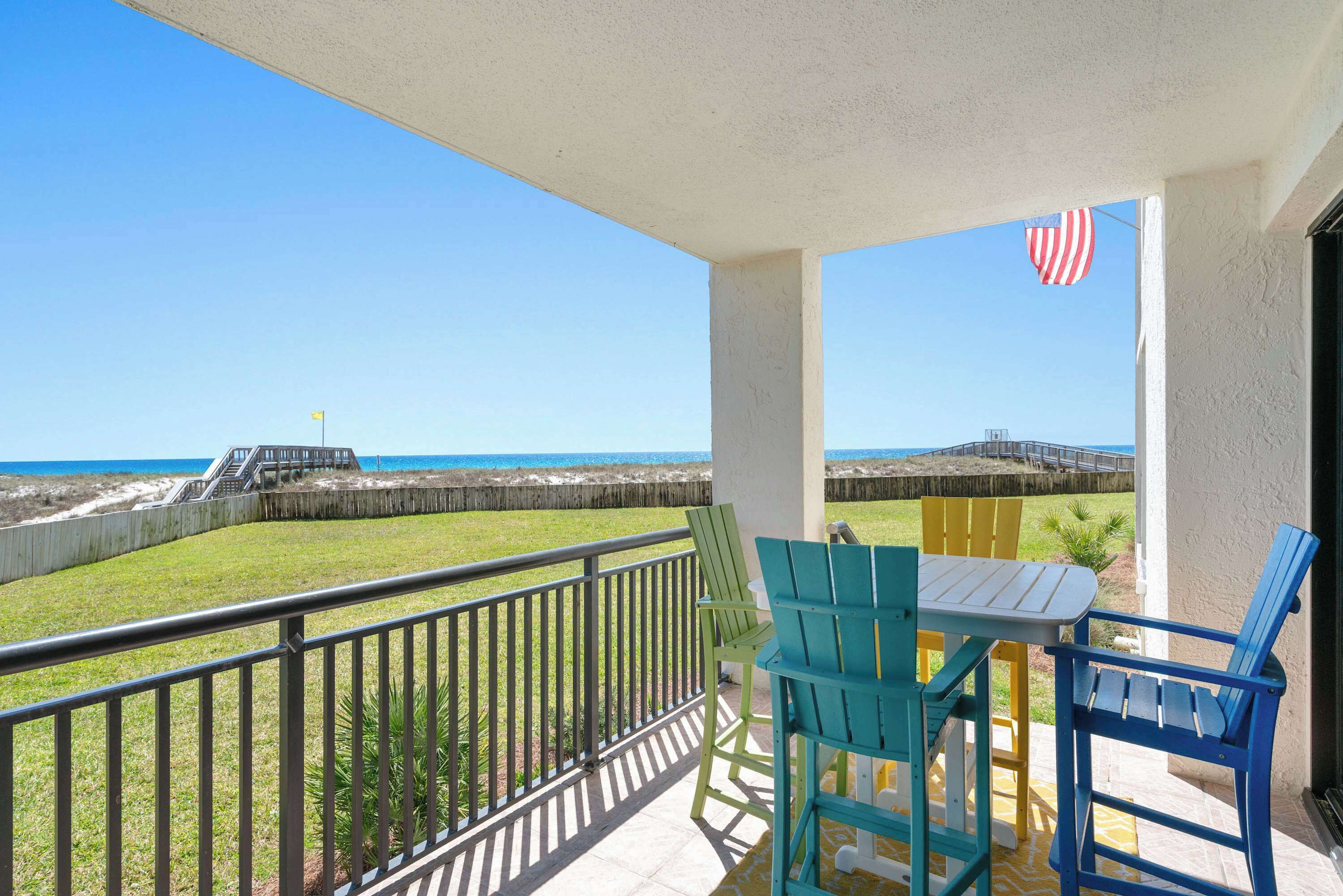 Un balcon avec vue sur la plage, un drapeau et du mobilier d’extérieur.