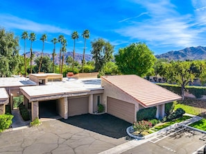 A modern house with a flat roof, a garage, and a landscaped garden. - Charming South Palm Desert Condo (Palm Desert)