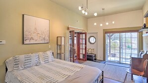 Een slaapkamer met een groot bed, een deur naar een balkon, een schilderij aan de muur en een plafondlamp.