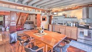 Een ruime keuken met een houten eettafel, moderne apparatuur en een trap naar een hoger gelegen verdieping.