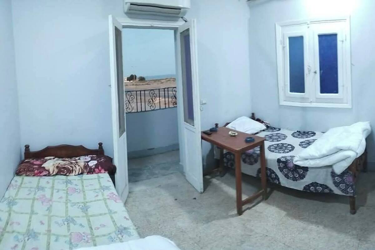 A small, compact room with a bed, a desk, a chair, a TV, and a window.