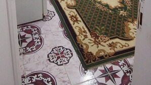 A room with a bed, a small table, a door, and a patterned carpet. - Marsa allan star (Marsa Alam)