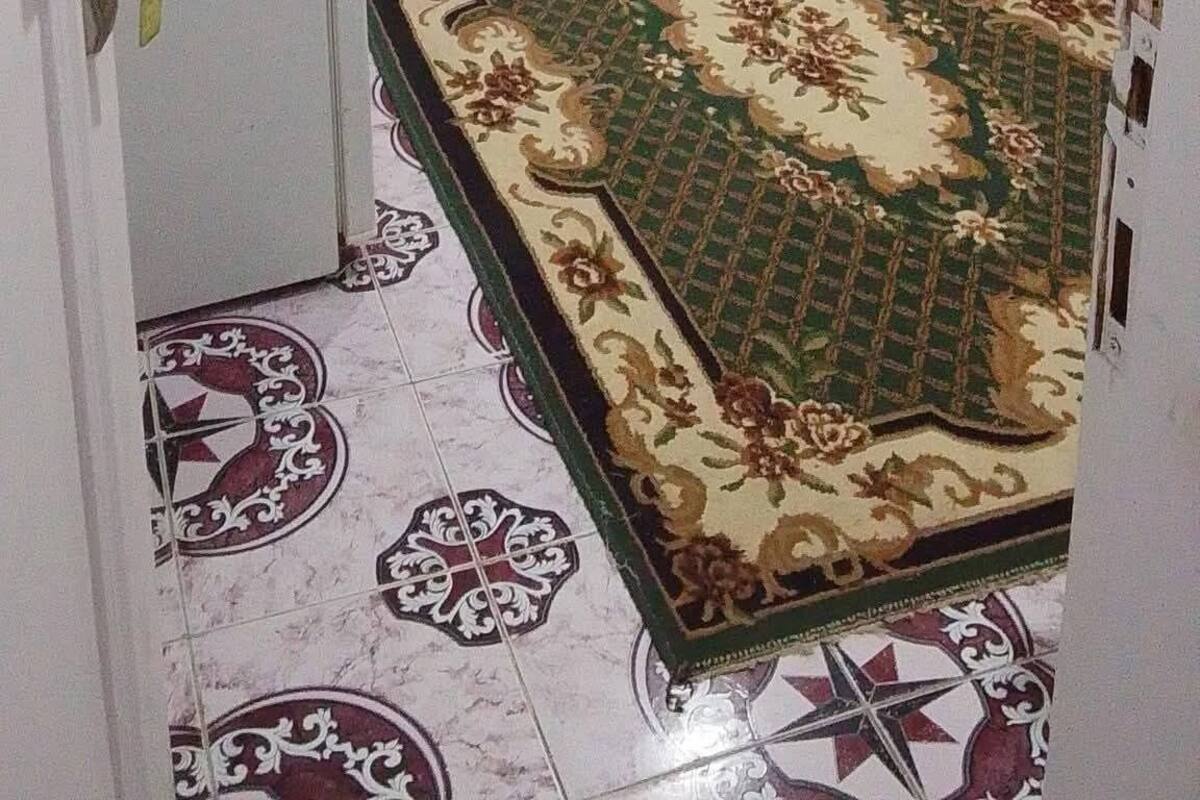 A room with a bed, a small table, a door, and a patterned carpet.