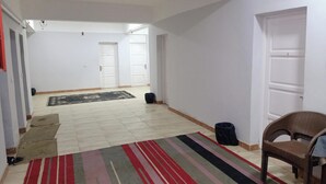 A spacious room with a tiled floor, a striped rug, a wicker chair, and a white door. - Marsa allan star (Marsa Alam)